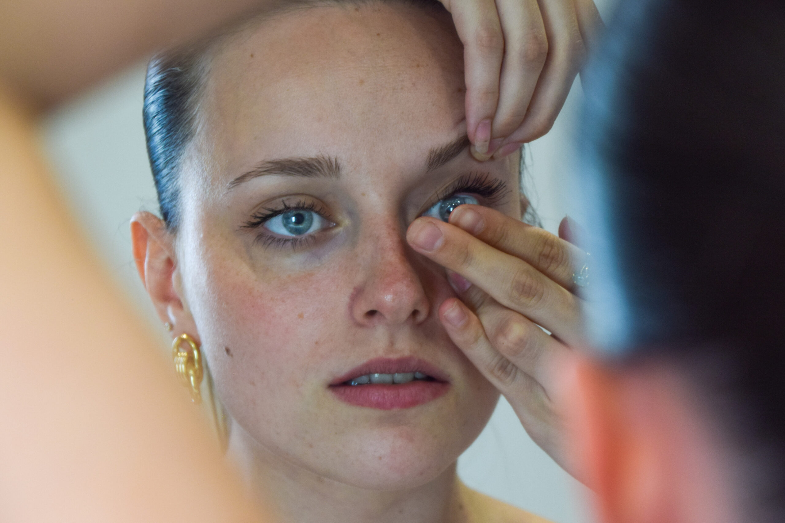 Une jeune femme met une lentille dans son oeil